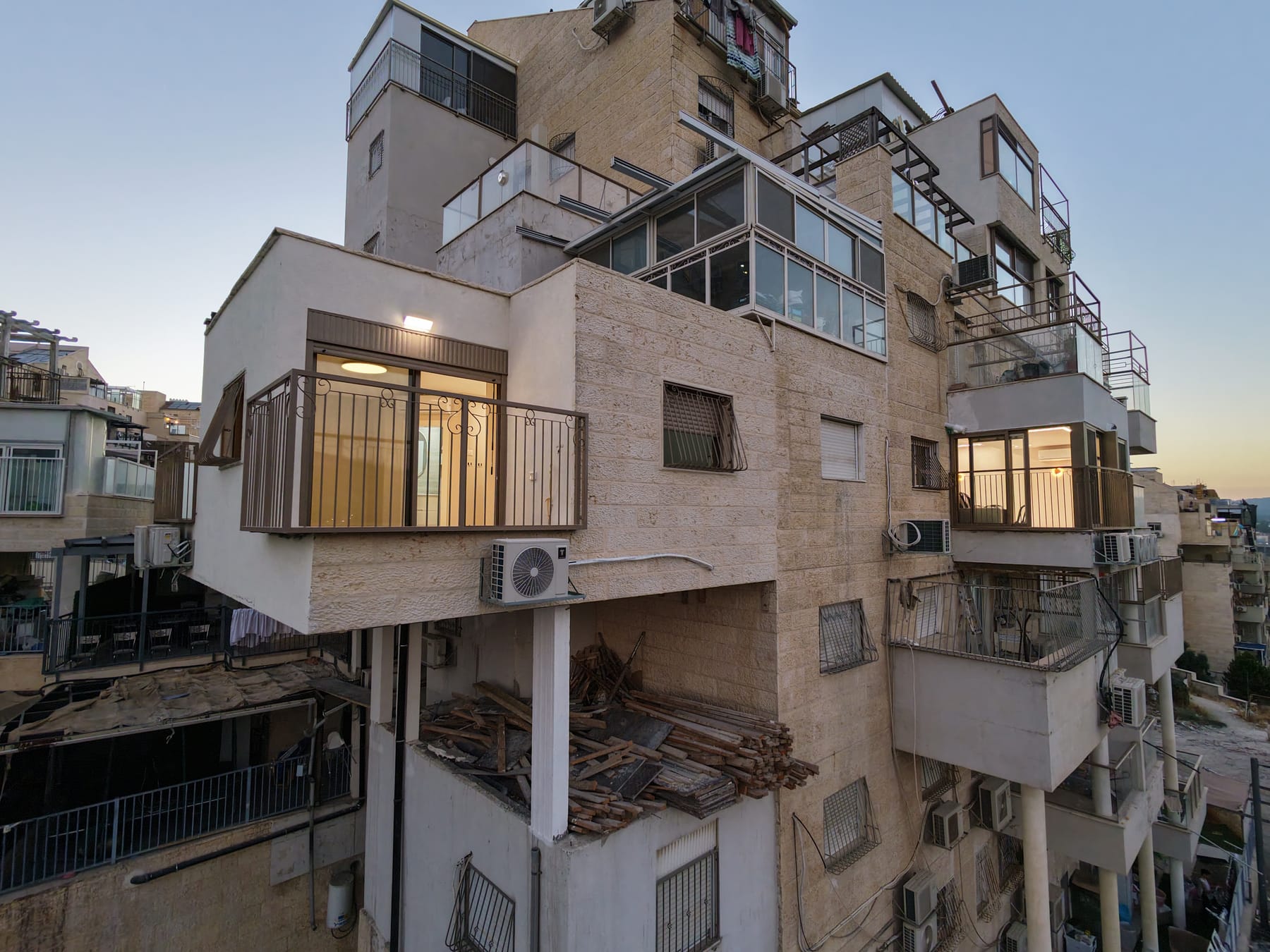 צילום רחפן בשעת דמדומים של ההרחבה שנבנתה על חזית בניין אבן, חלונותיה מוארים