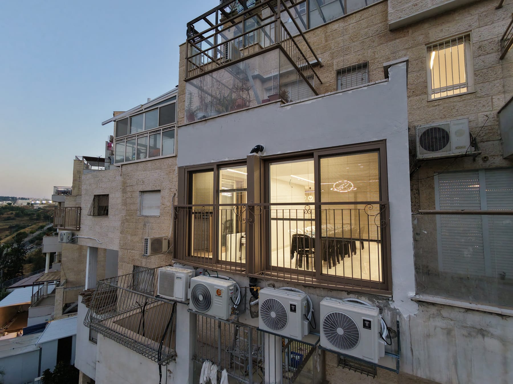 חזית הבניין עם מפרץ הסלון המואר, בדמדומים